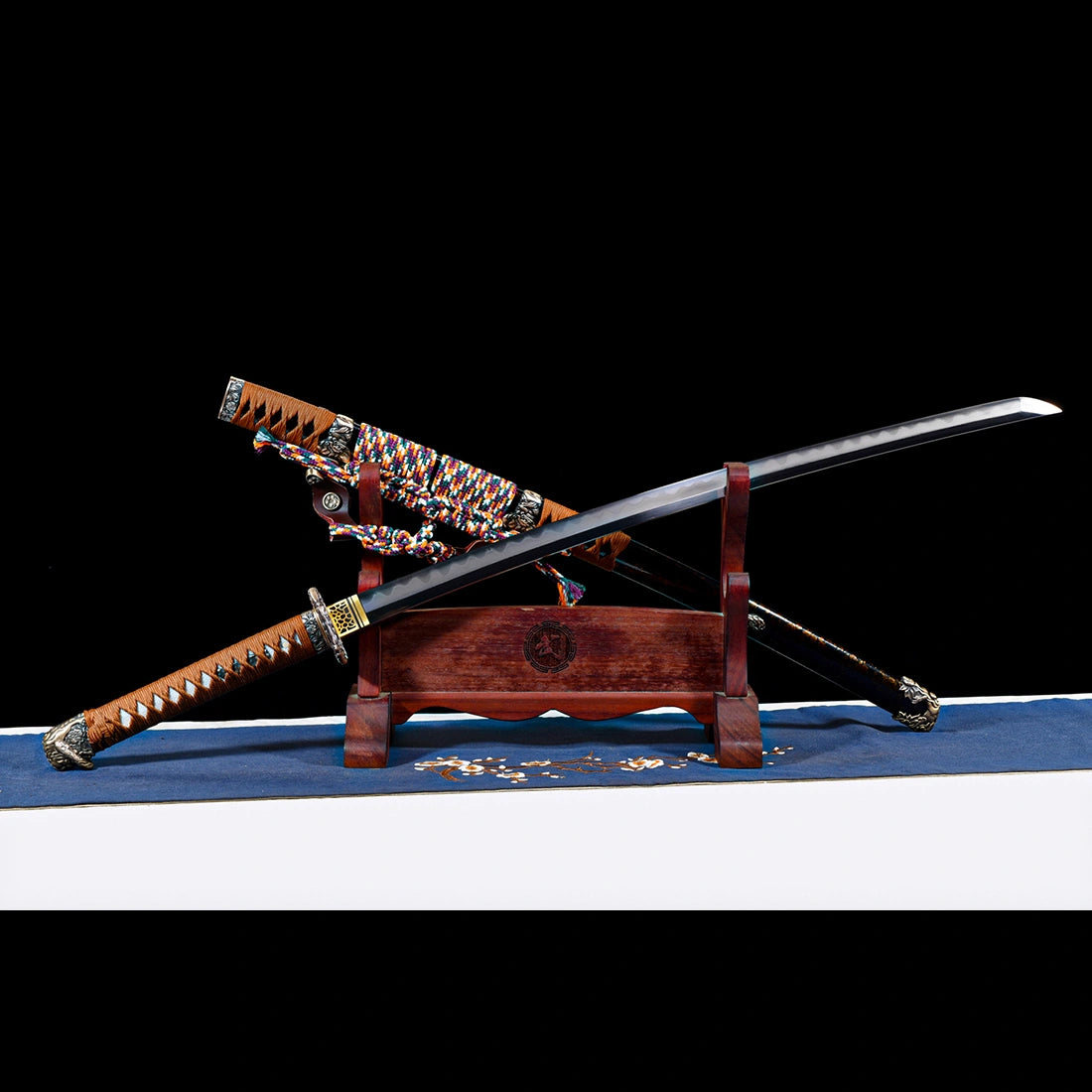 Unsheathed Dragonheir Damascus steel Tachi blade crossed over gold-flecked lacquered Saya on wooden display rack