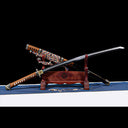 Unsheathed Dragonheir Damascus steel Tachi blade crossed over gold-flecked lacquered Saya on wooden display rack
