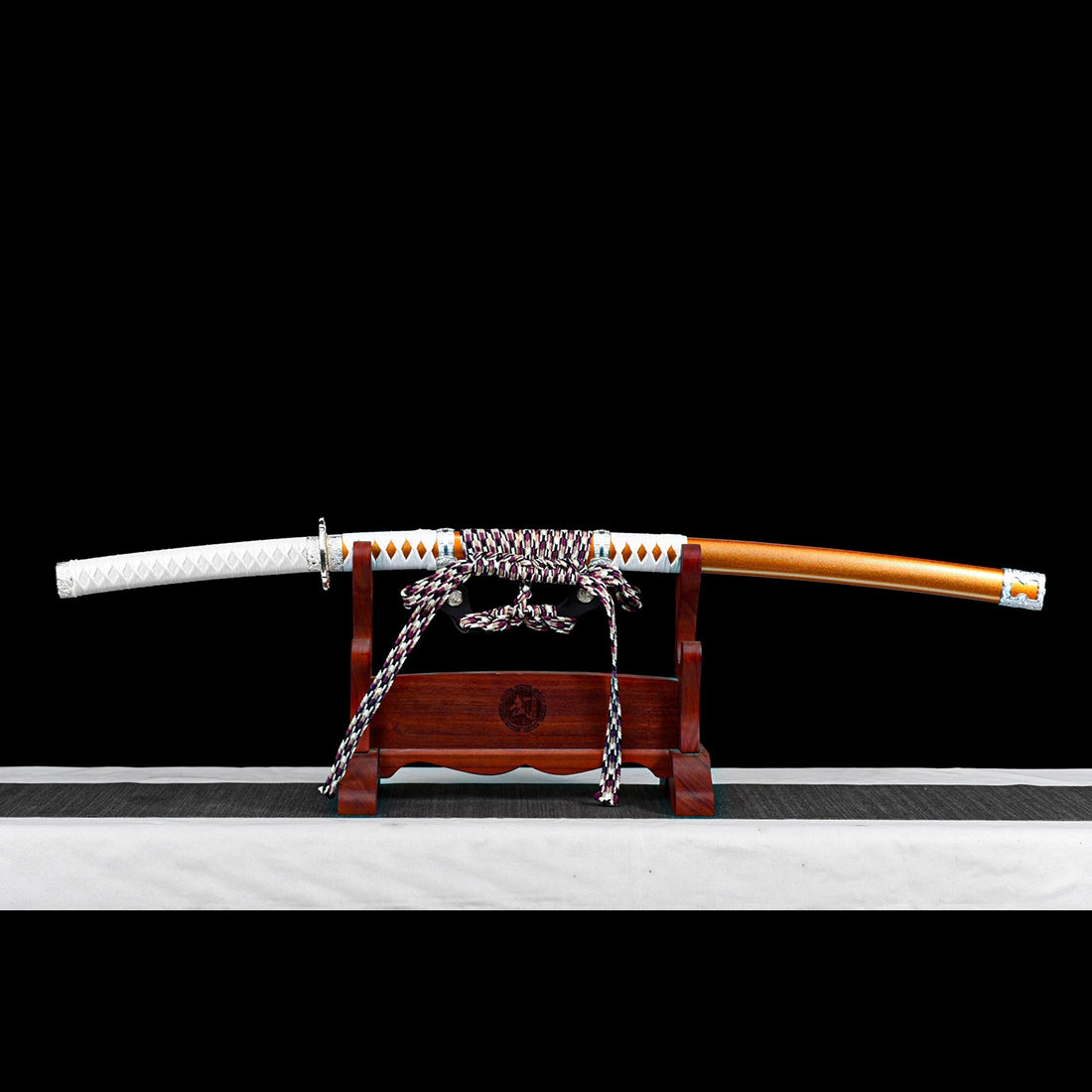 Hand-forged japanese tachi sword in orange lacquered scabbard resting on wooden stand