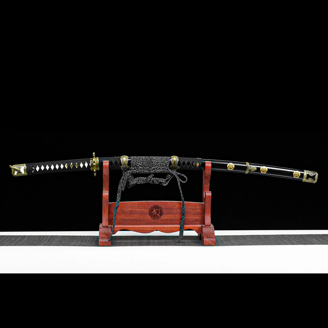 Sheathed Murasame tachi sword with lacquered black pear wood scabbard on wooden display stand