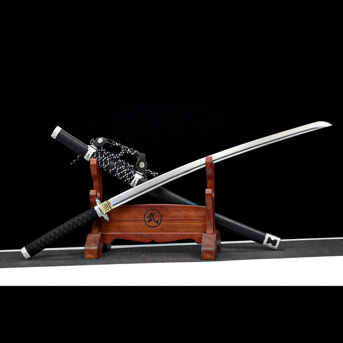 Hand-forged 60 HRC Damascus steel tachi sword blade resting over black textured marble-finish scabbard with ashi hangers