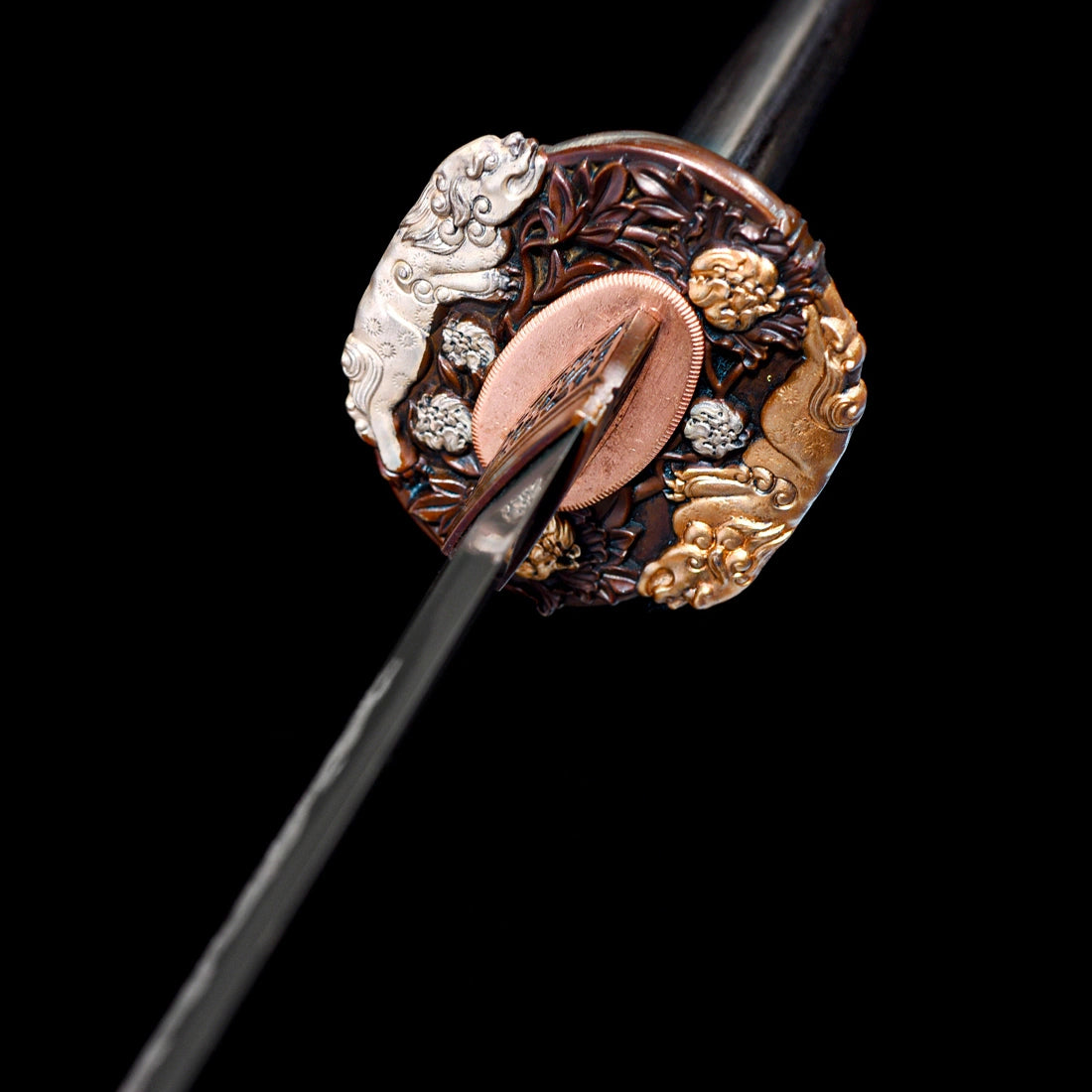 Macro view of hand-carved copper Tsuba guard with gold and silver Shishi lion inlays and copper Habaki on Tyrantclaw Tachi