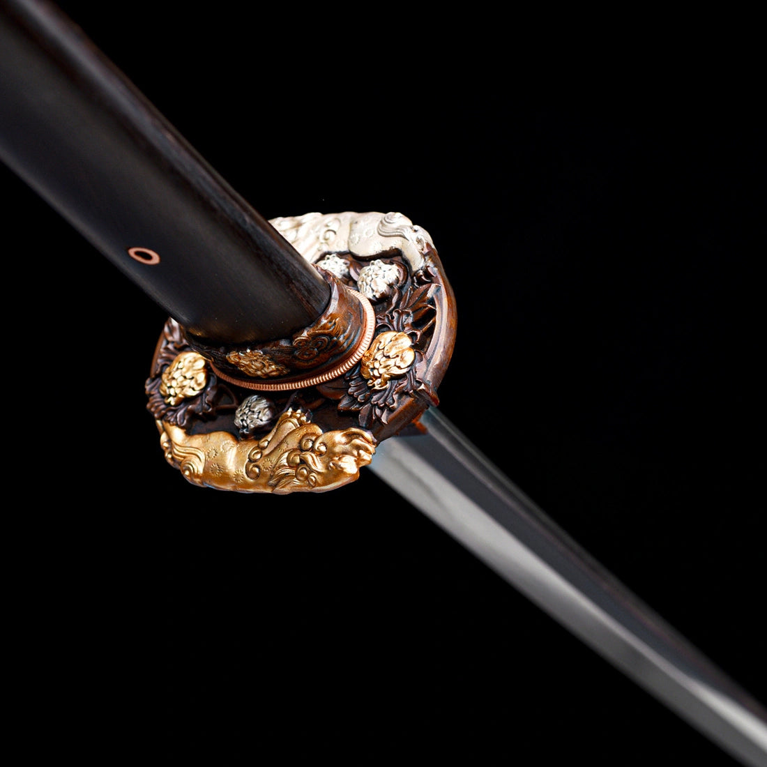Angled macro shot of relief copper Tsuba featuring gold and silver Shishi guardian lion inlays and ebony Tsuka handle